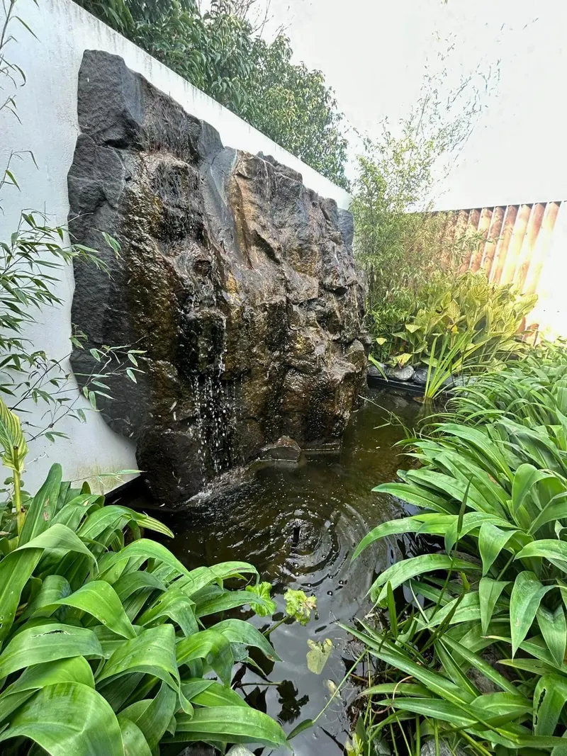 Stone waterfall feature set into a planted garden