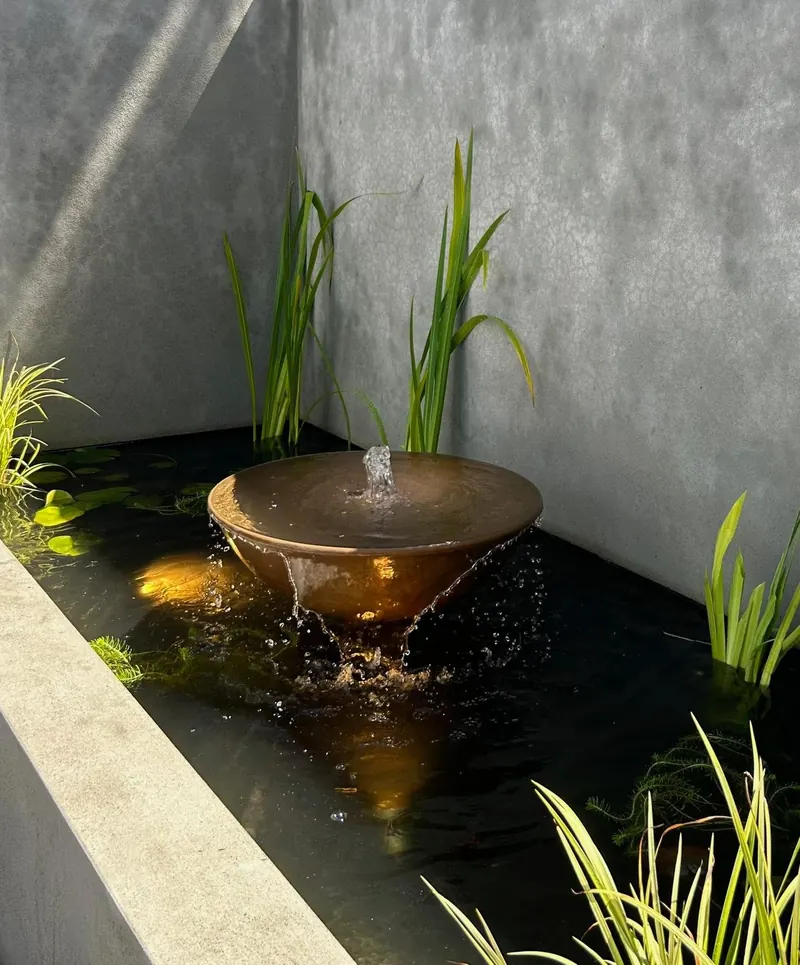 Pond with pink water lilies and lily pads among stone features